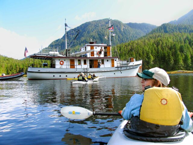 A kayaker in front of a boat.