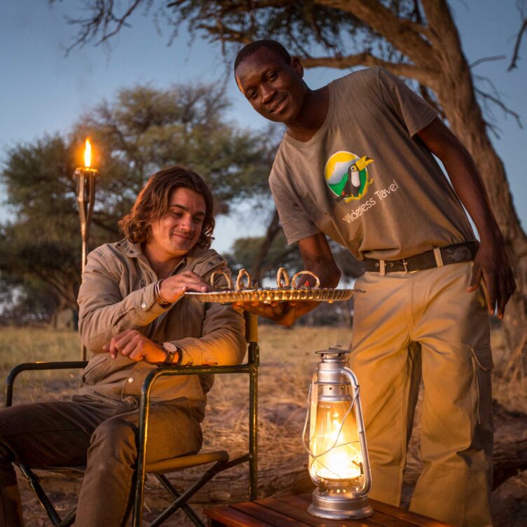 A Wilderness Travel Botswana staff member serving food.