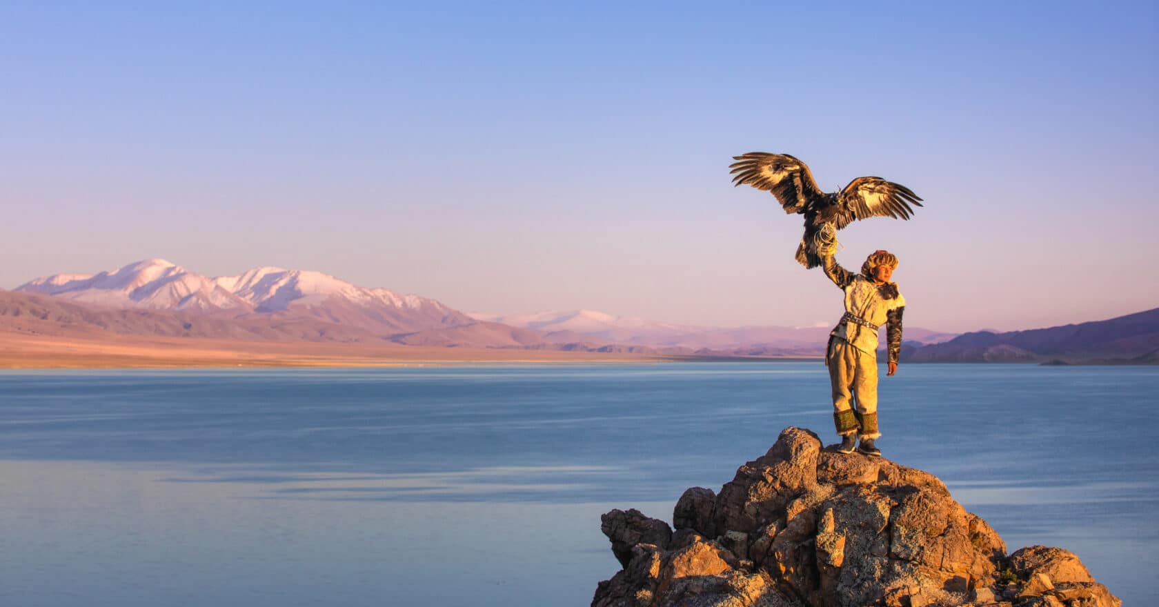 Young kazakh eagle hunter with his golden eagle