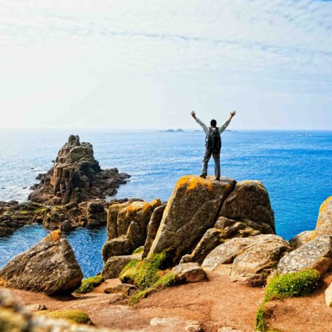 A hiker posing on a rock by the sea.