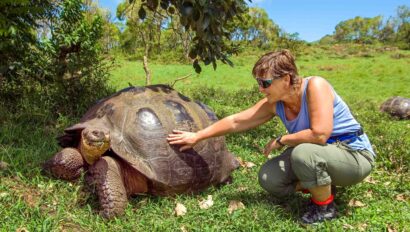 A tourist alongside a giant tortoise.