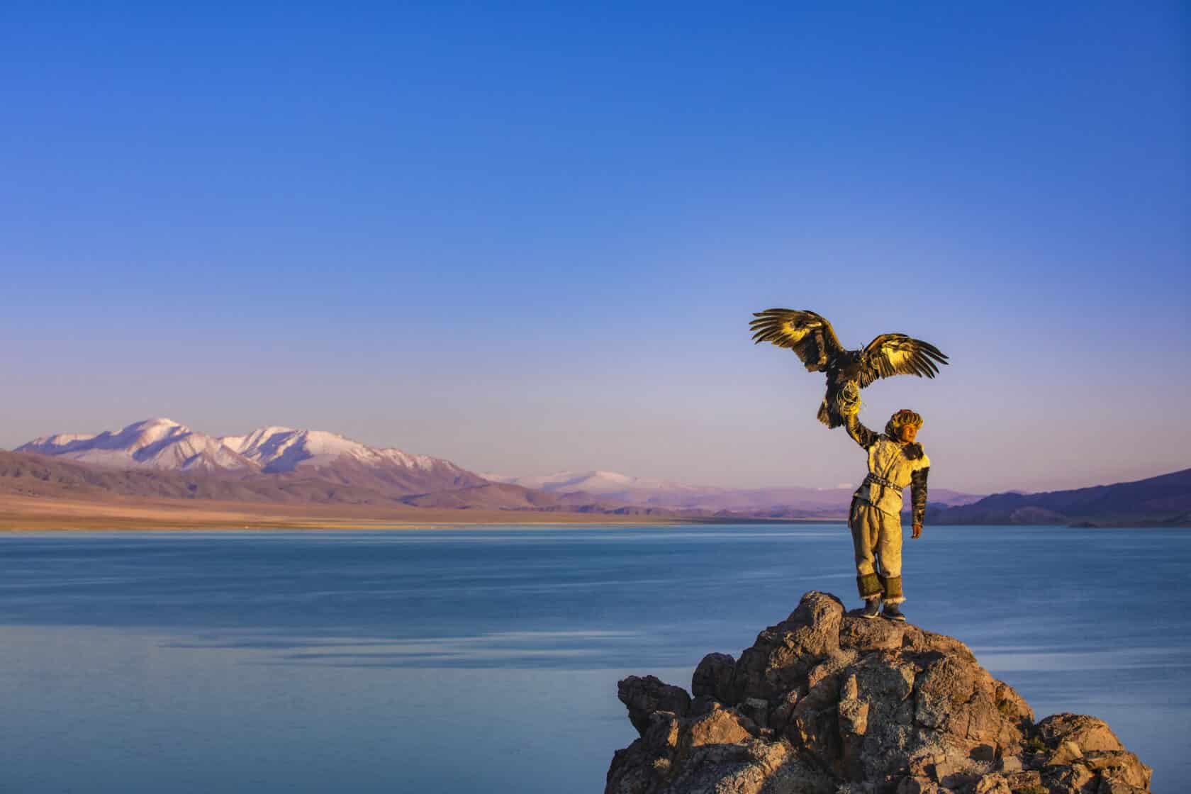 Young kazakh eagle hunter with his golden eagle.