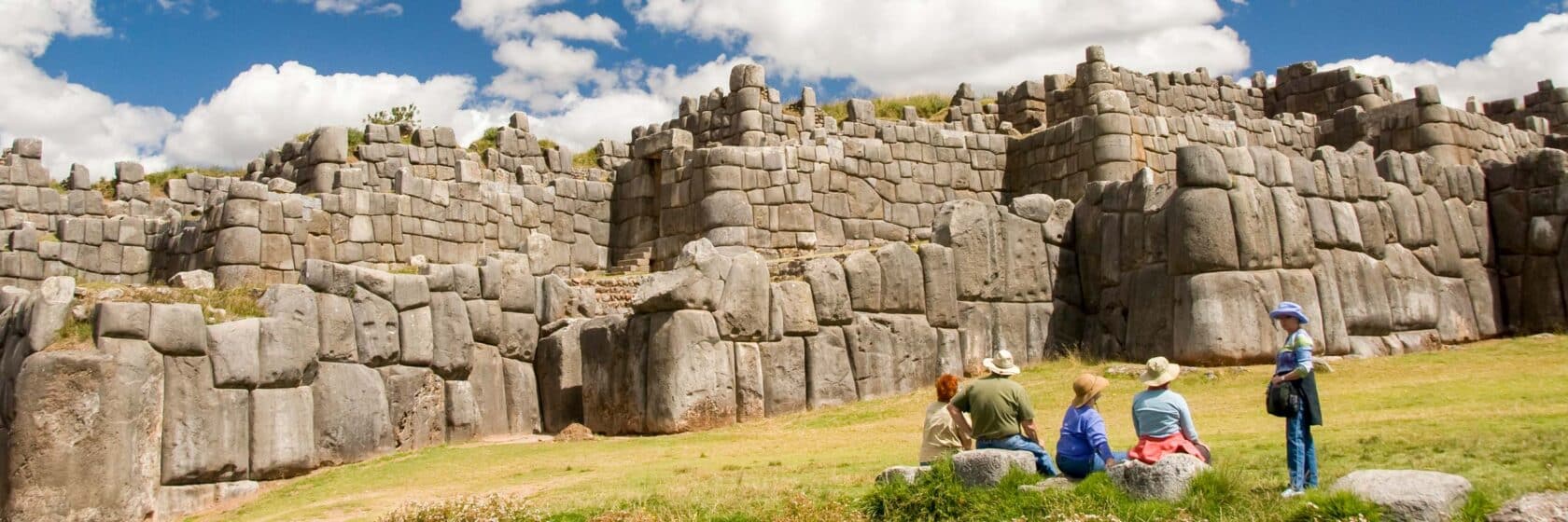 A group of tourists relaxing by a wall.